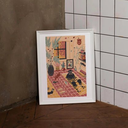 Framed “Me Time” art print by Max Kolo, featuring a cozy illustrated room with plants, warm tile flooring, a window, shelves, and a relaxed black dog, displayed leaning against a textured concrete wall beside white square tiles on a wooden floor.