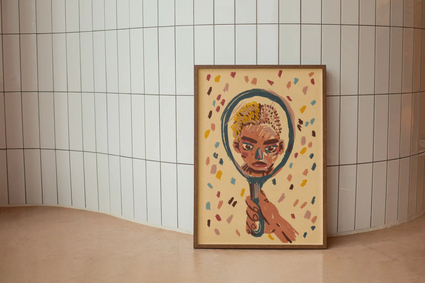 Framed artwork "mirror" print by NYC artist Max Kolo on the floor against a curved white tiled wall, featuring a stylized painted face reflected in a hand-held mirror, modern surreal illustration poster.