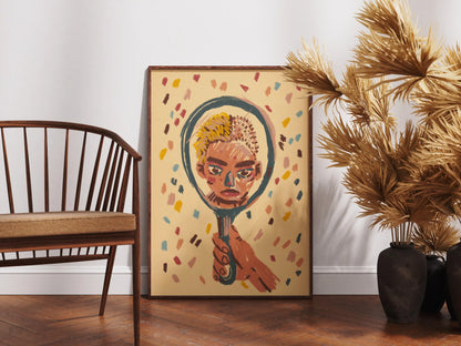 Framed "Mirror" art print by Max Kolo on a wooden floor beside a wooden chair and decorative dried plants, featuring a stylized painted face reflected in a hand-held mirror.