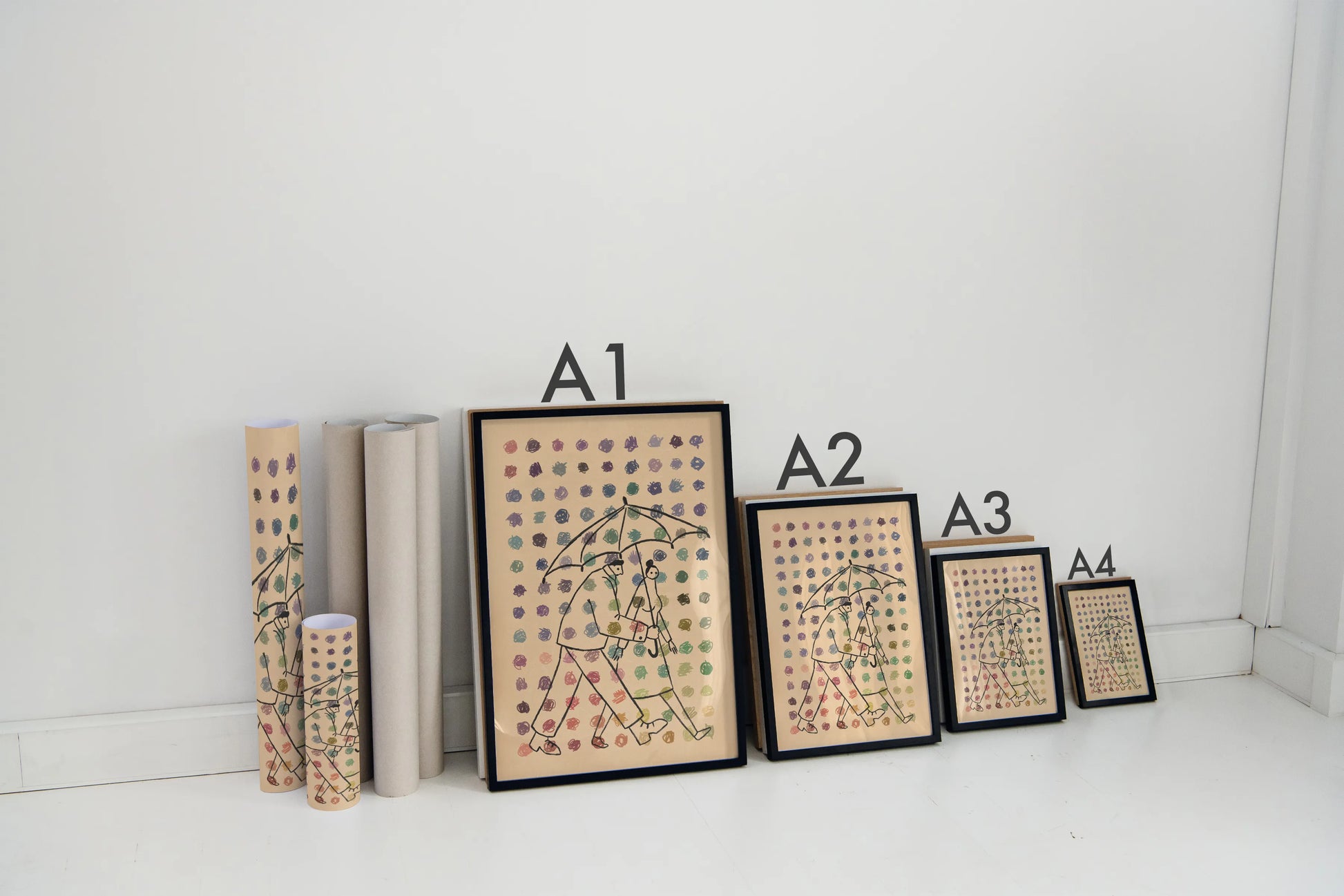 Set of framed prints with sizes A1 to A4 on a white surface. Artwork of two people under an umbrella with dots of multiple colors in the foreground. Artwork by New York City Artist Max Kolo.